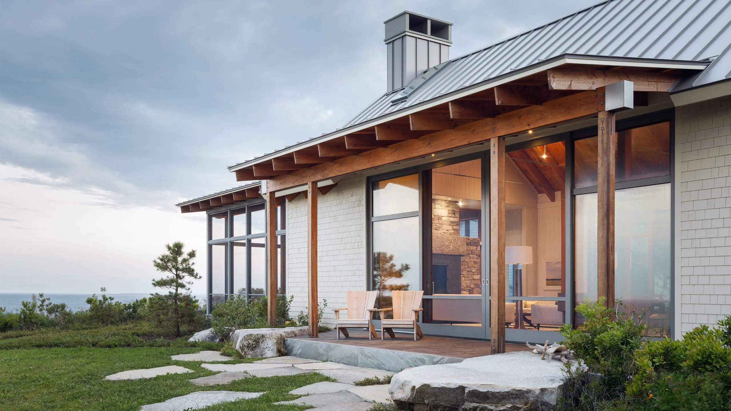 Modern beach house with large windows and wooden deck overlooking ocean