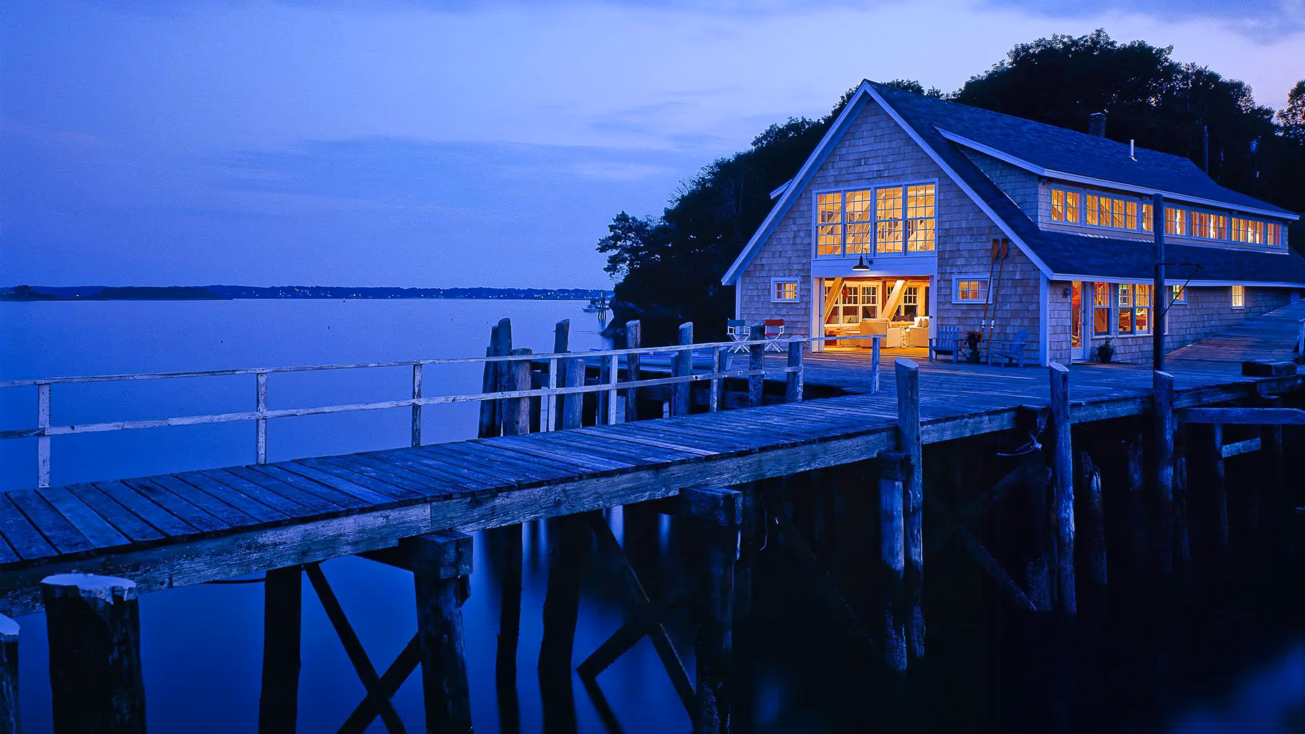 Cozy wooden cabin on stilts with warm lights by a calm blue evening water