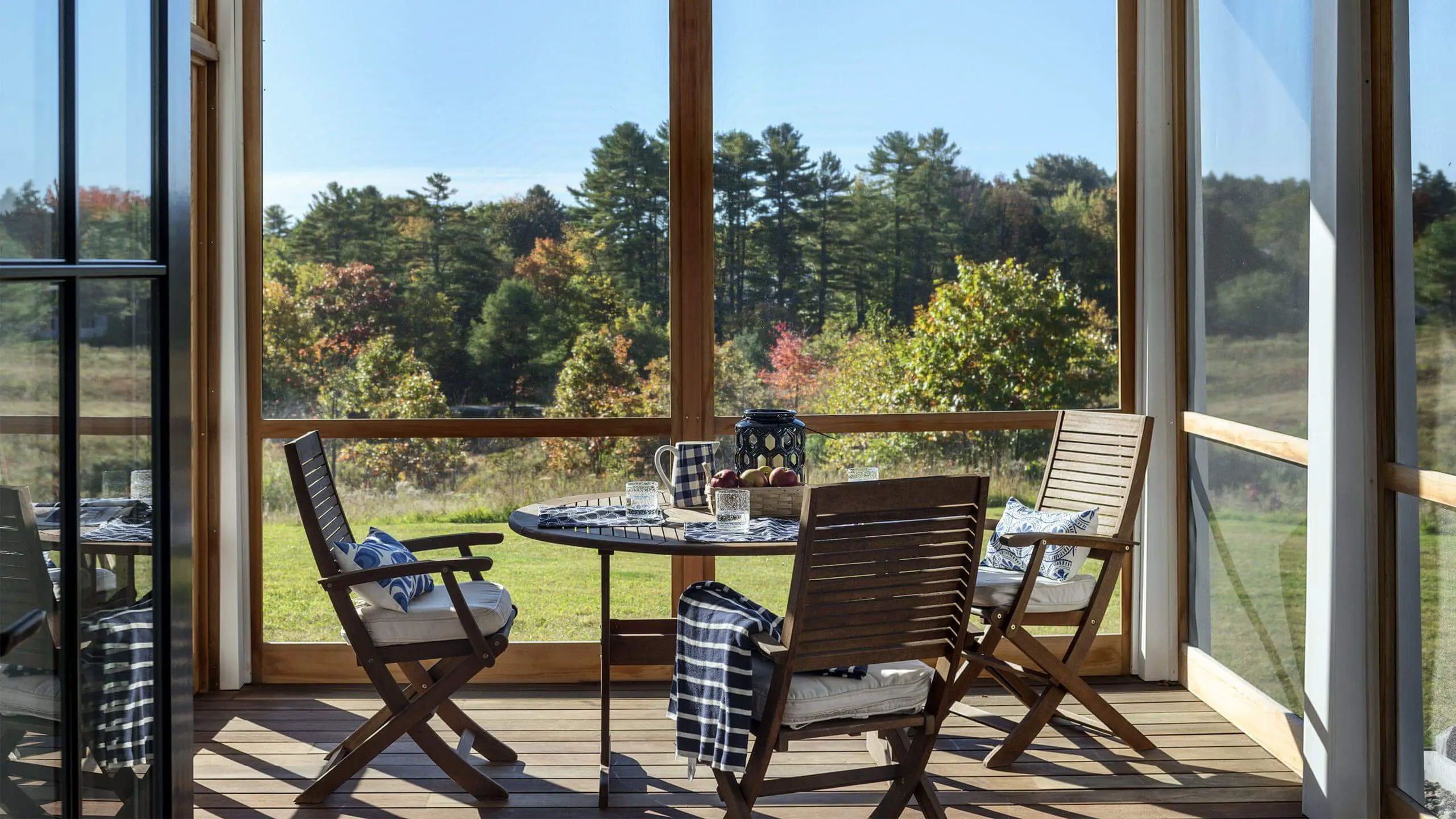 Cozy screened porch with wooden chairs overlooking autumn forest landscape