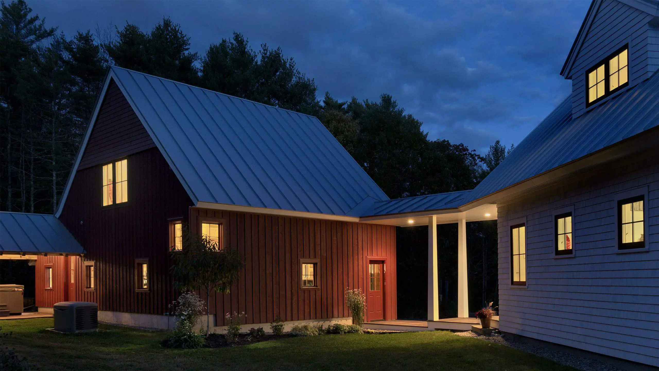 Modern wooden house with warm glowing windows at twilight in forest