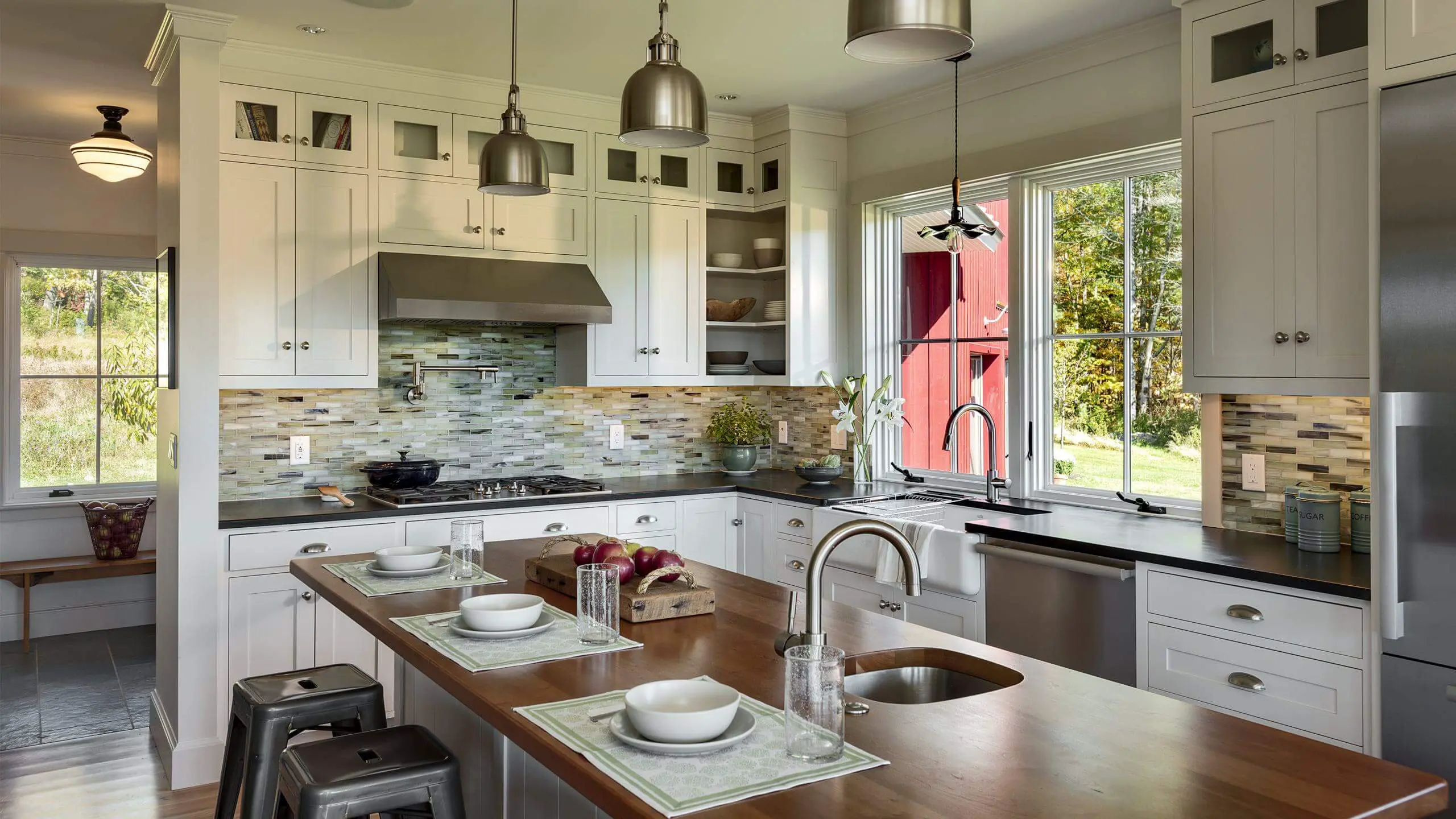 Modern farmhouse kitchen with white cabinets, wooden island, and red barn view