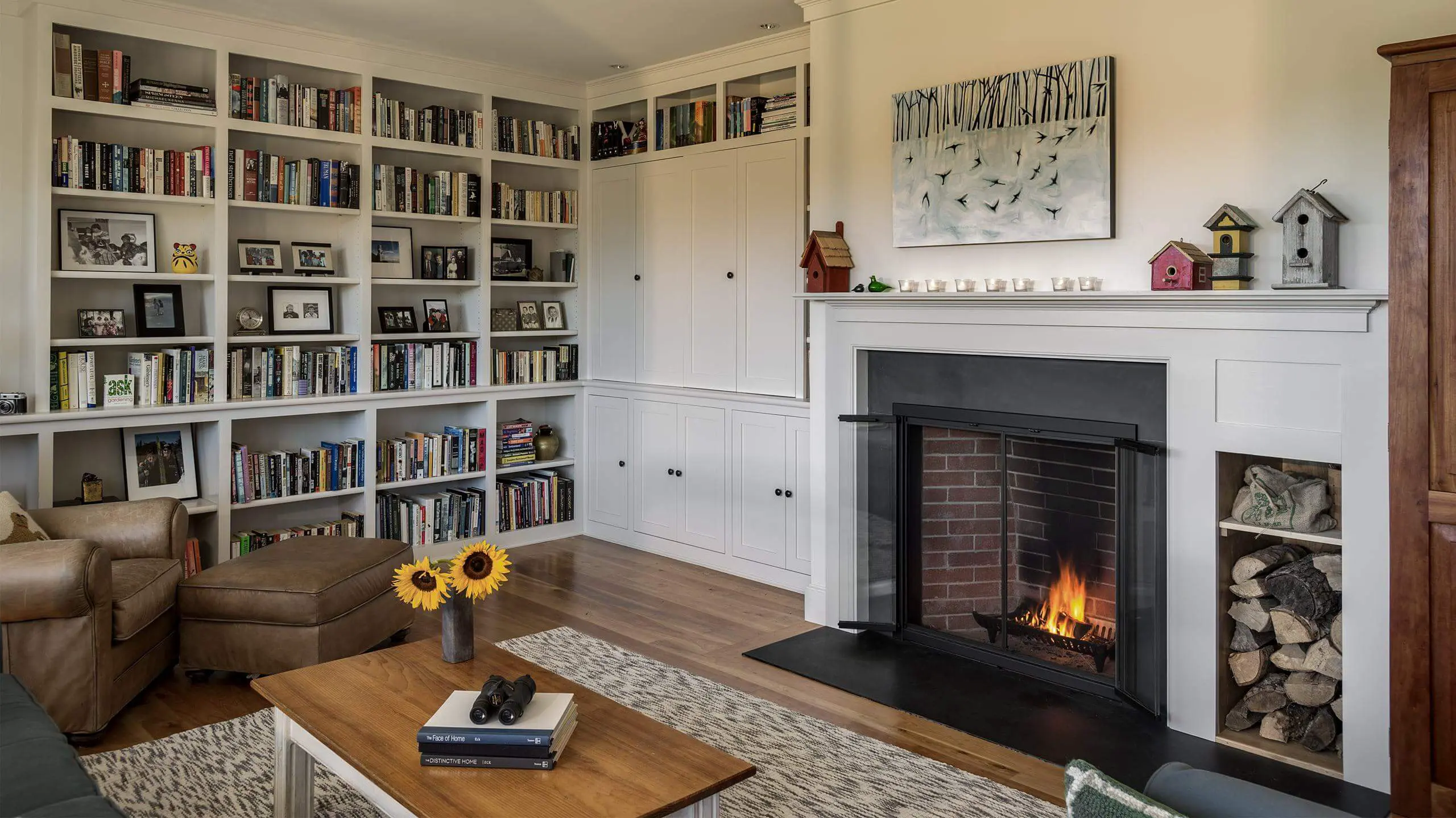 Cozy living room with built-in bookshelves, fireplace, and sunflowers