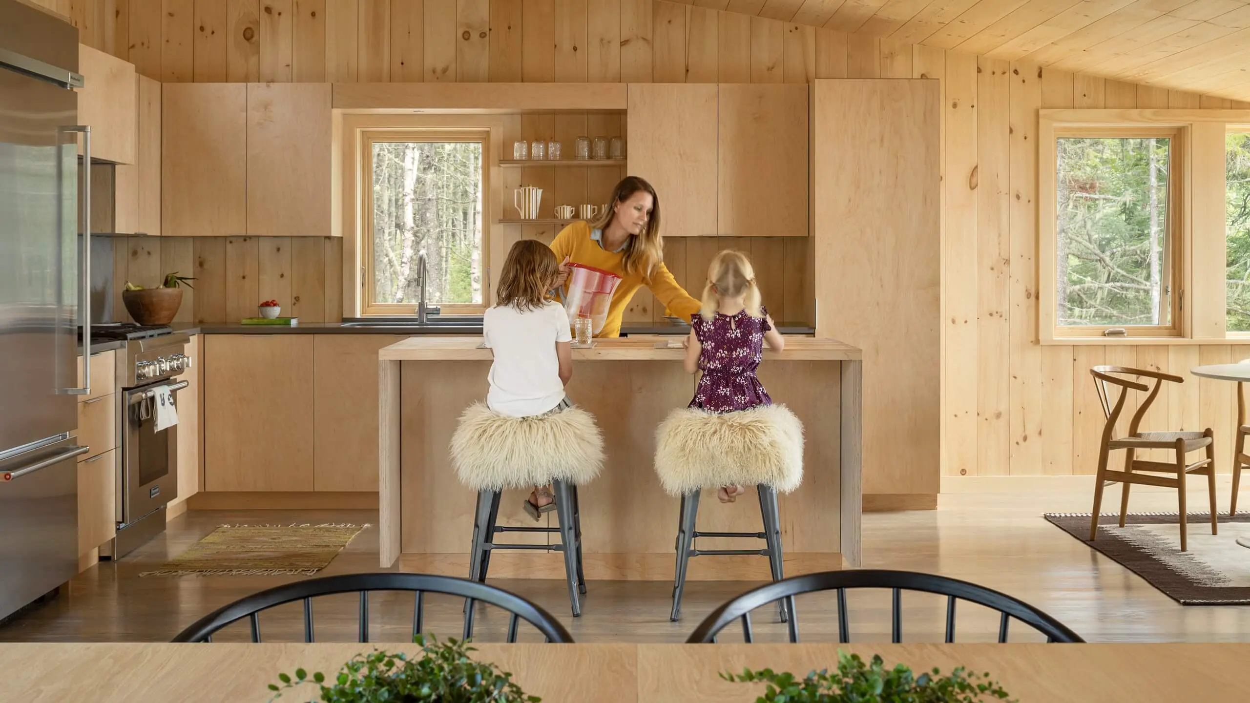 Woman with two children at kitchen island with fluffy bar stools