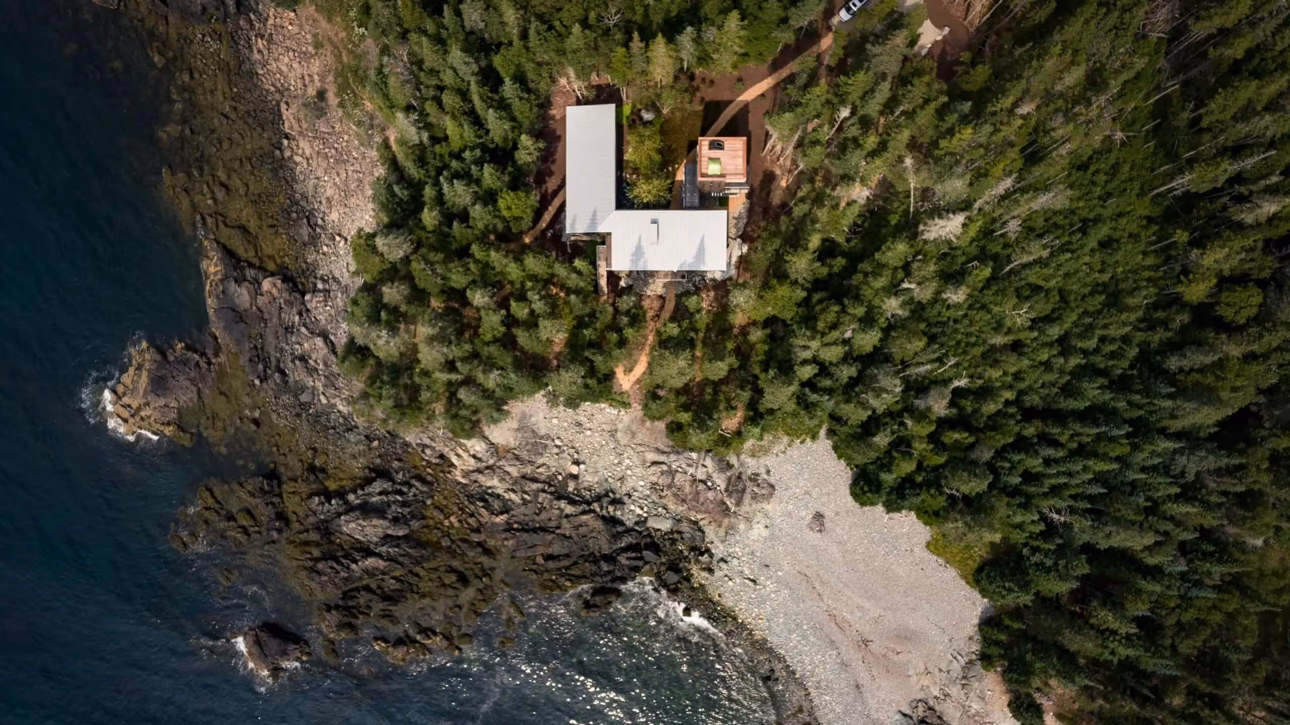 Aerial view of white buildings nestled in rocky coastal forest landscape