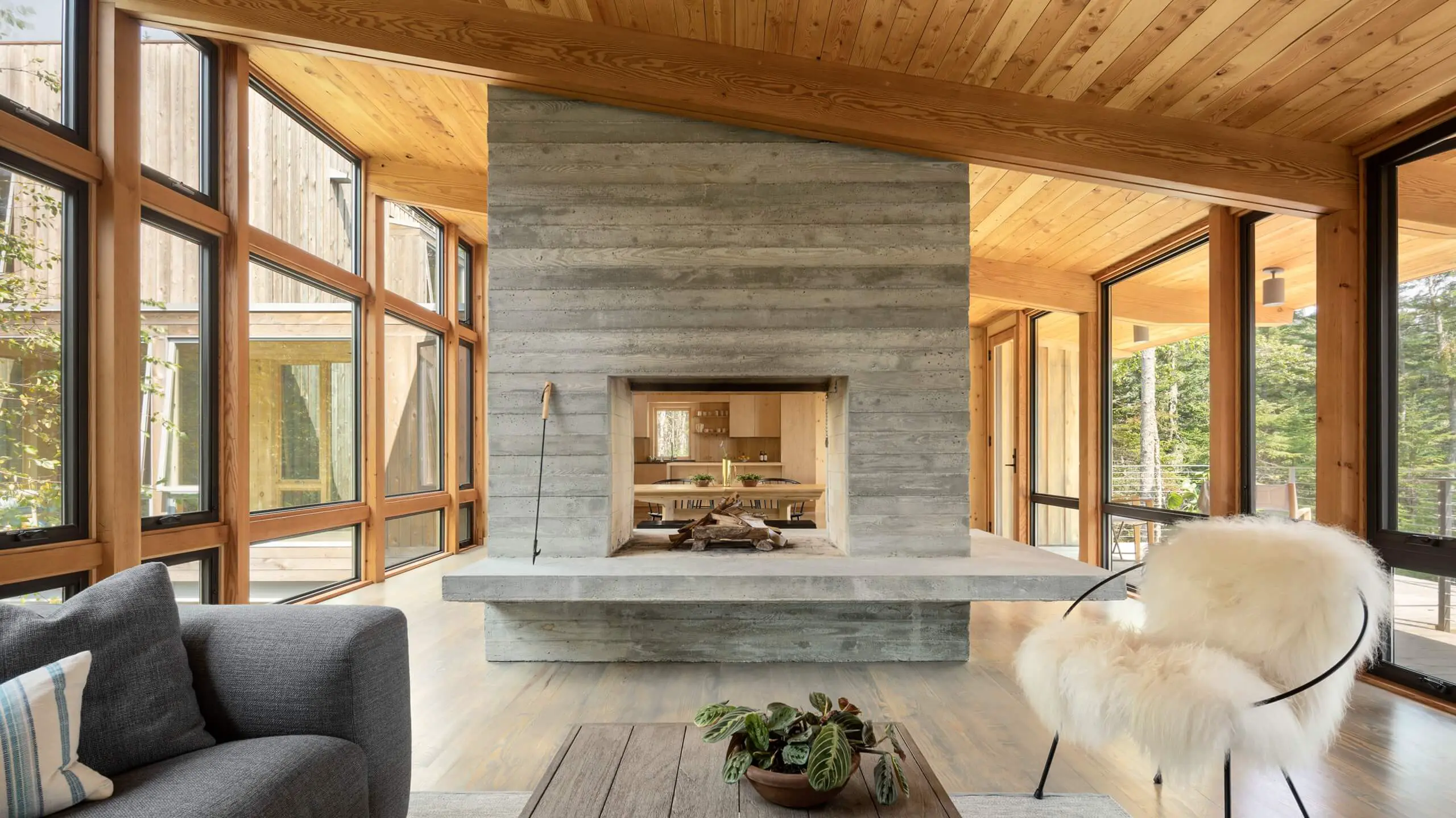 Modern wood and concrete interior with two-sided fireplace and large windows