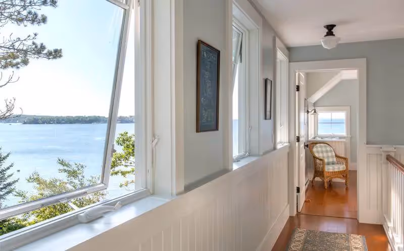Bright hallway with large windows overlooking serene lake and trees