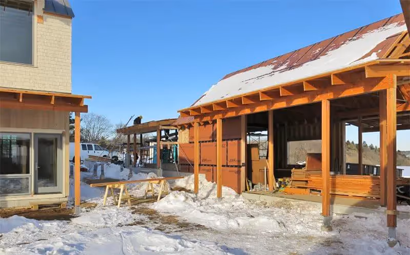 Wooden building under construction in snowy winter landscape