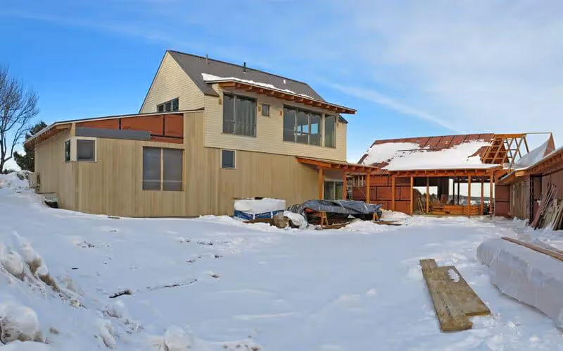 Snow-covered construction site with wooden houses and unfinished buildings