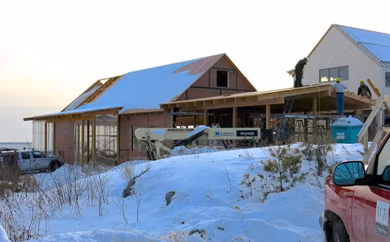 Winter house construction site with snow-covered ground and building materials