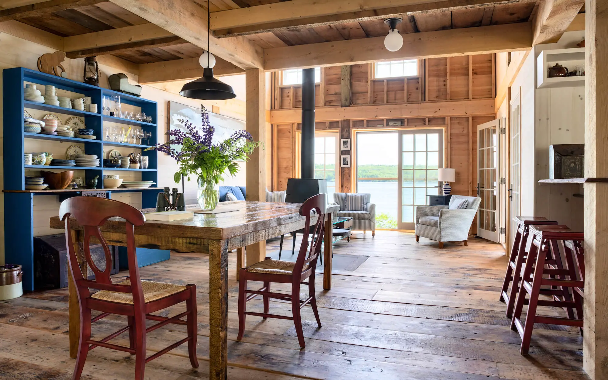 Rustic wooden dining area with blue shelves, wooden table, and large windows