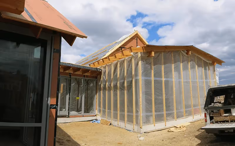 House under construction with wooden frame and protective plastic sheeting