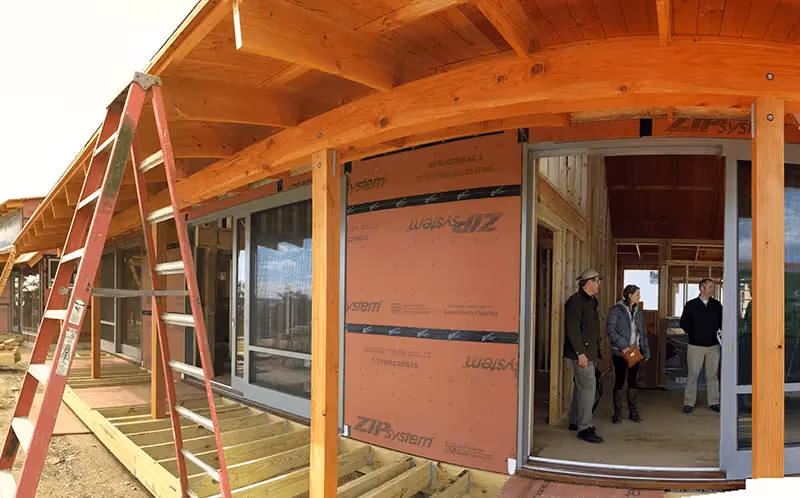 Wooden building under construction with workers and red ladder