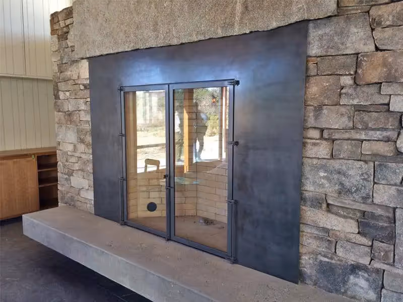 Modern steel-framed glass doors set in stone wall with concrete ledge