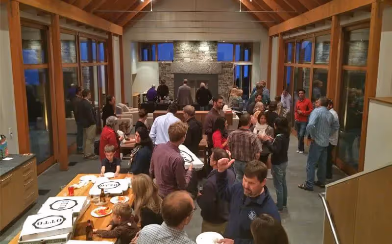 Crowded social gathering in a wooden and stone interior with people mingling