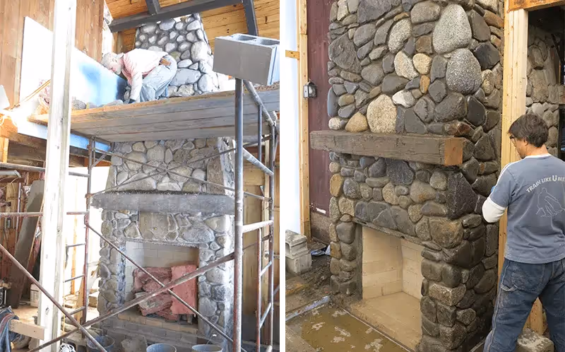 Stone fireplace construction with scaffolding and workers in progress