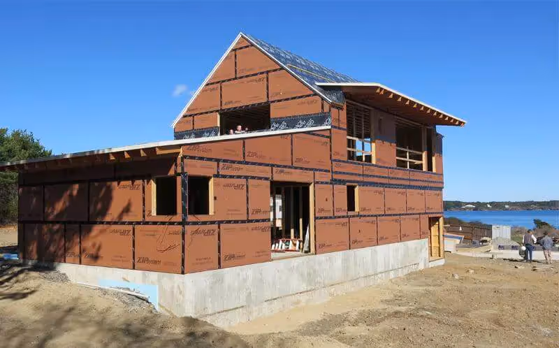 Two-story house under construction with waterfront view and solar panels