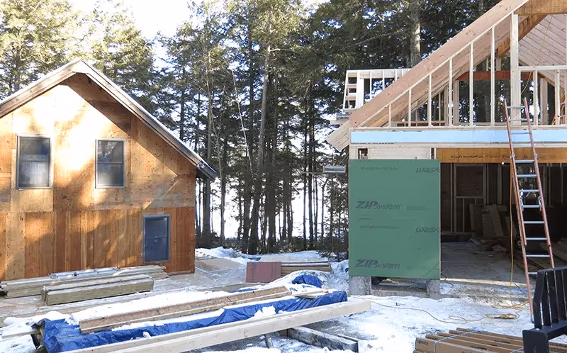 Wooden house construction site with framing and lumber in snowy forest