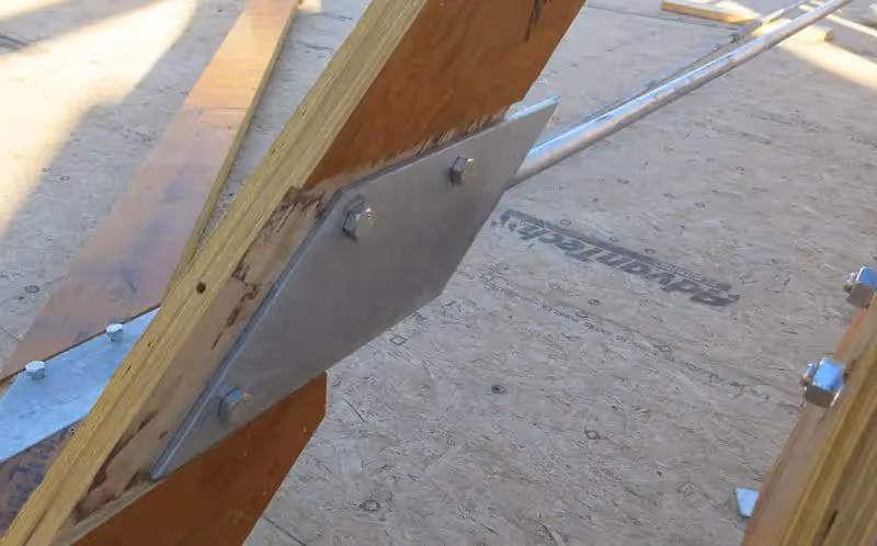 Metal angle bracket connecting wooden beams in construction framing