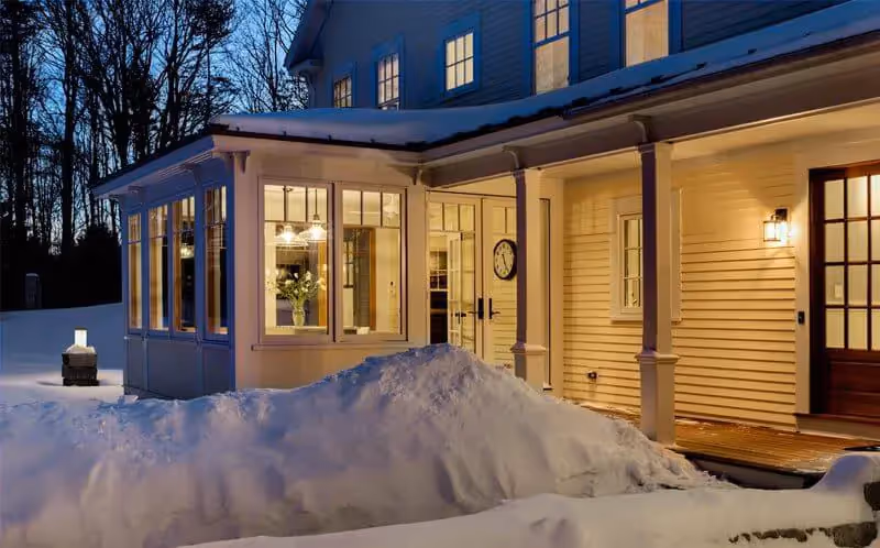 Cozy winter evening, warm house lights against snowy landscape at dusk