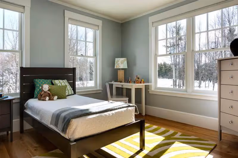 Cozy bedroom with large windows overlooking snowy winter landscape