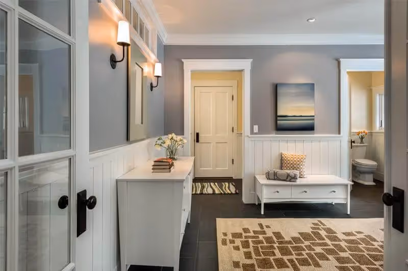 Modern entryway with white wainscoting, bench, and coastal artwork
