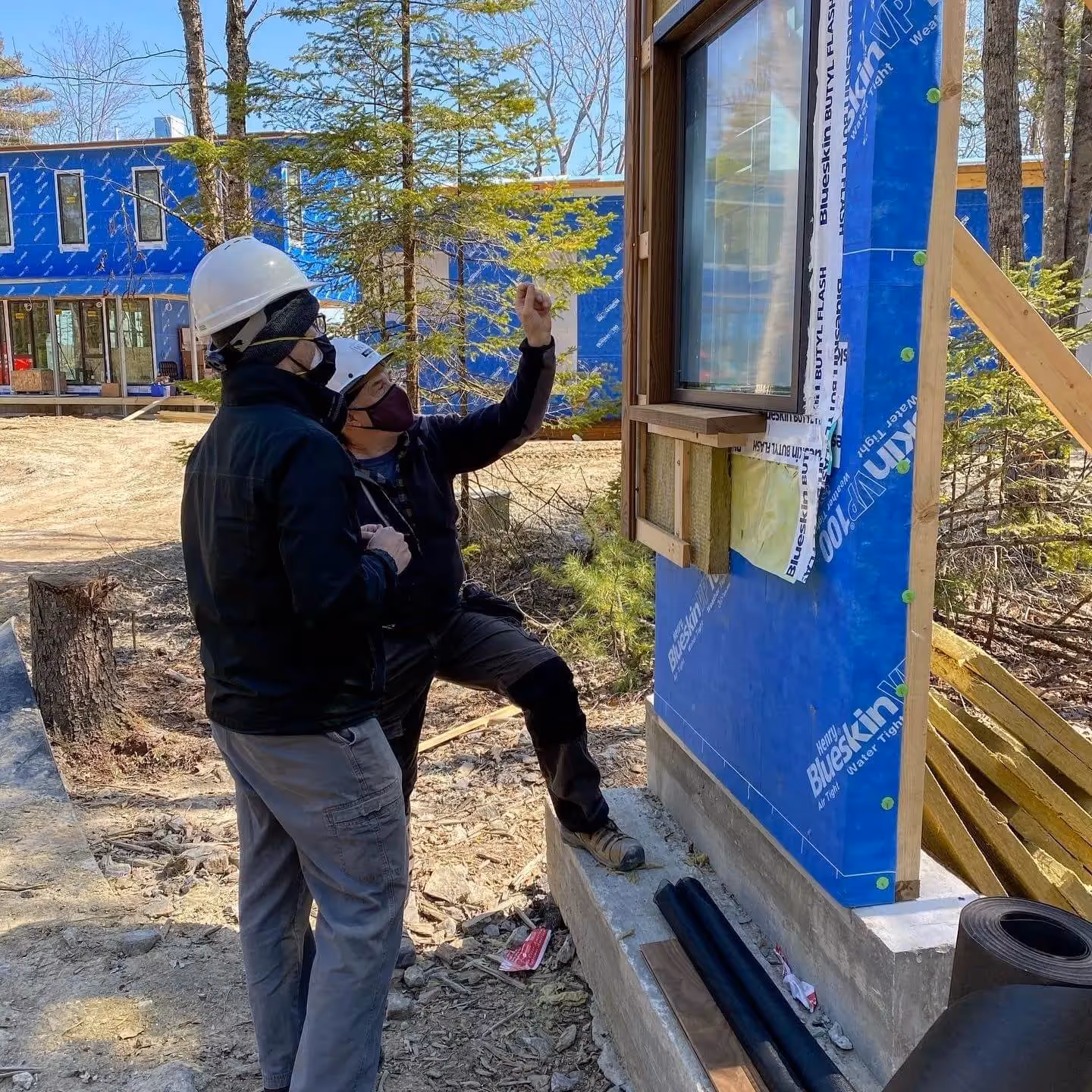 Construction workers inspect window installation at new building site