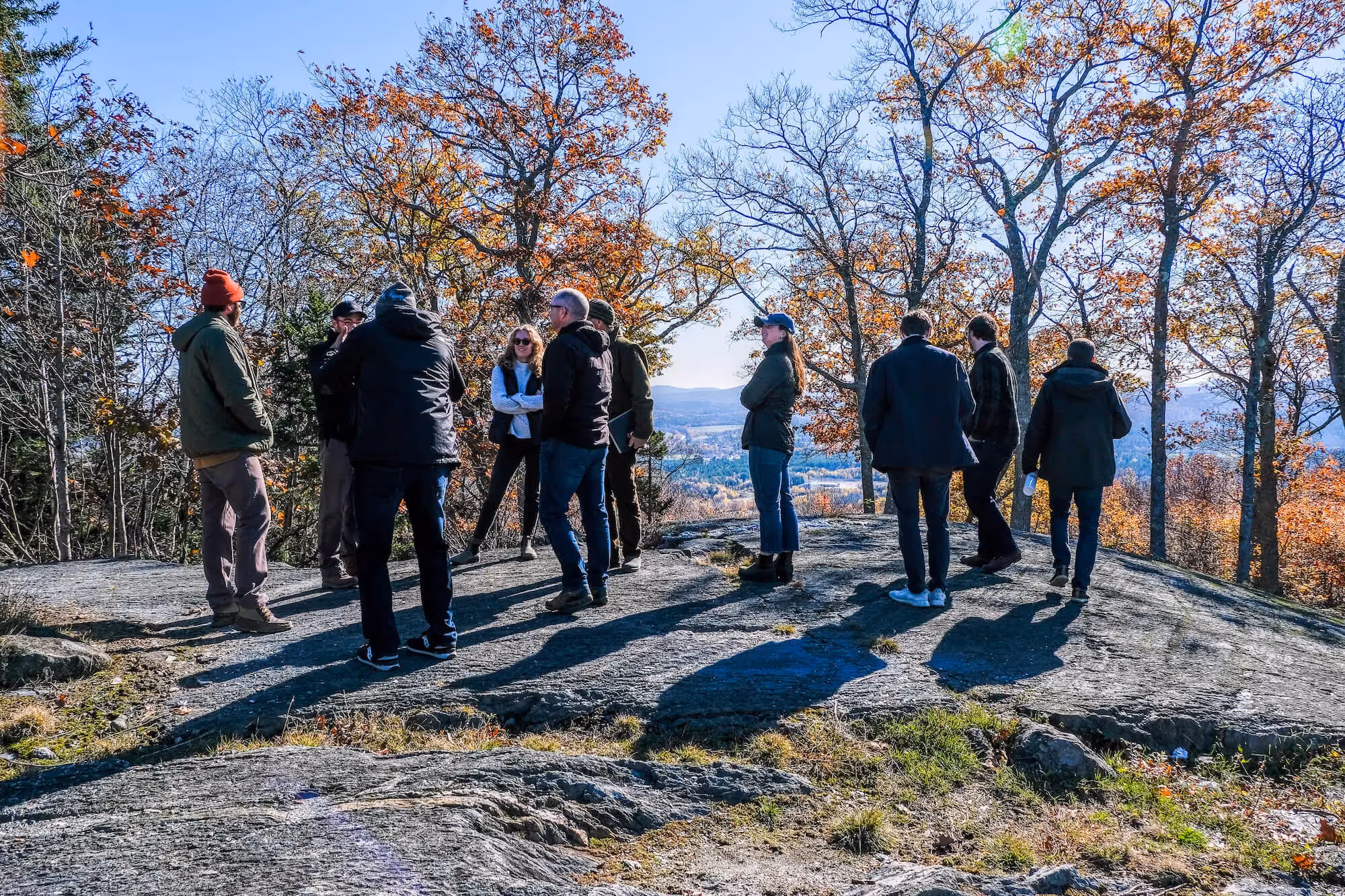 Group of people overlooking valley from rocky viewpoint in autumn