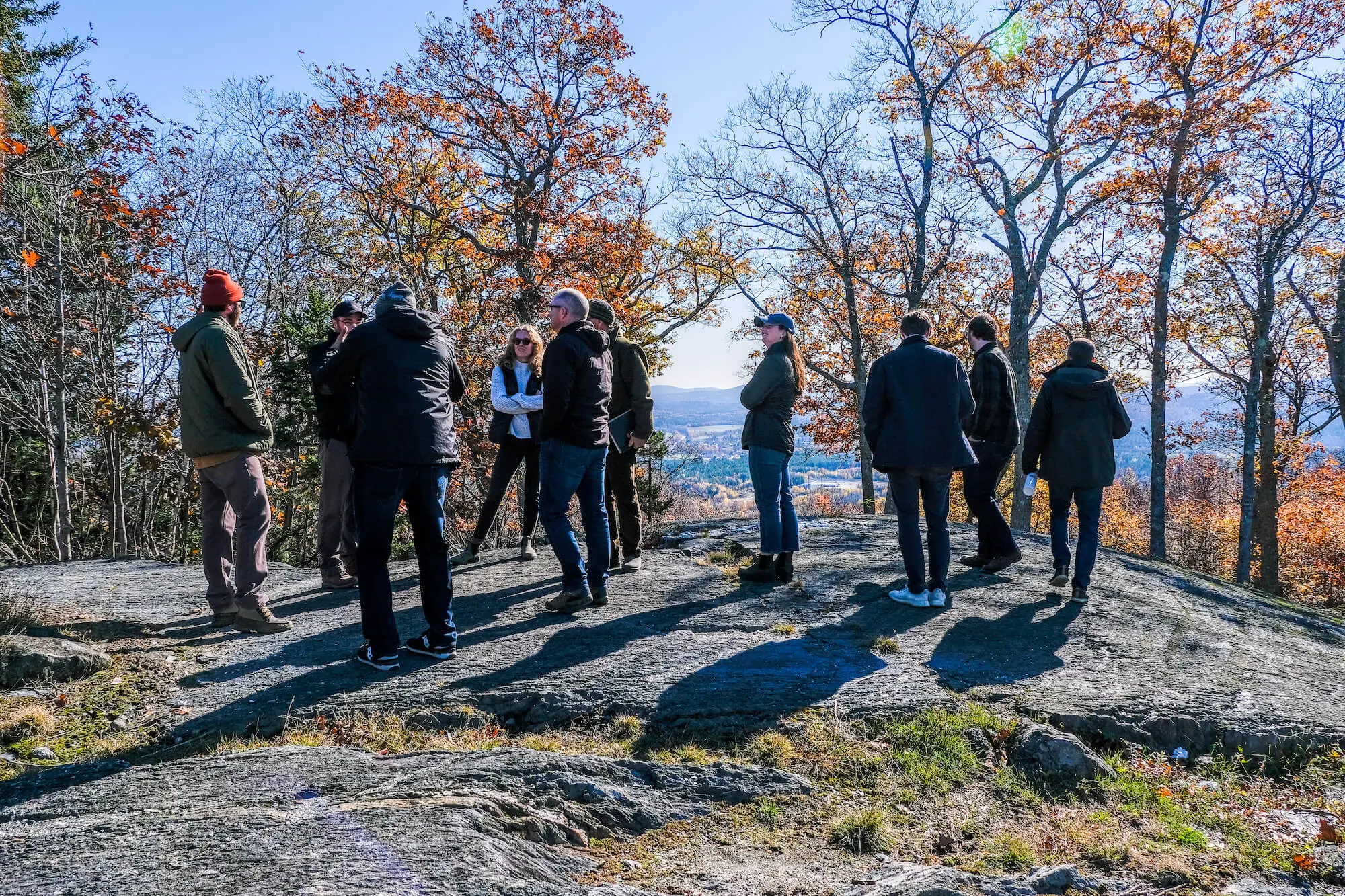Group of people overlooking valley from rocky viewpoint in autumn