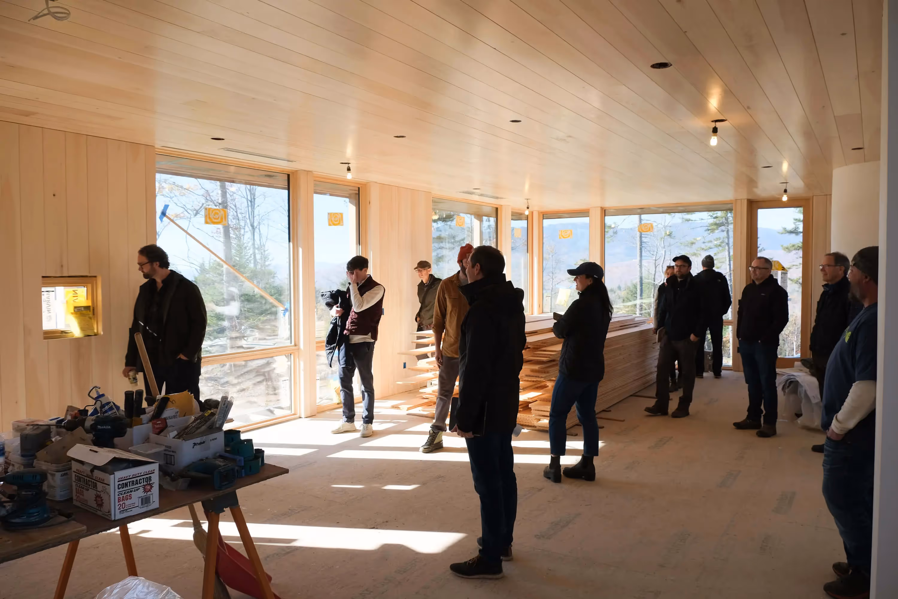 Construction workers gather in a sunlit wooden building during site inspection