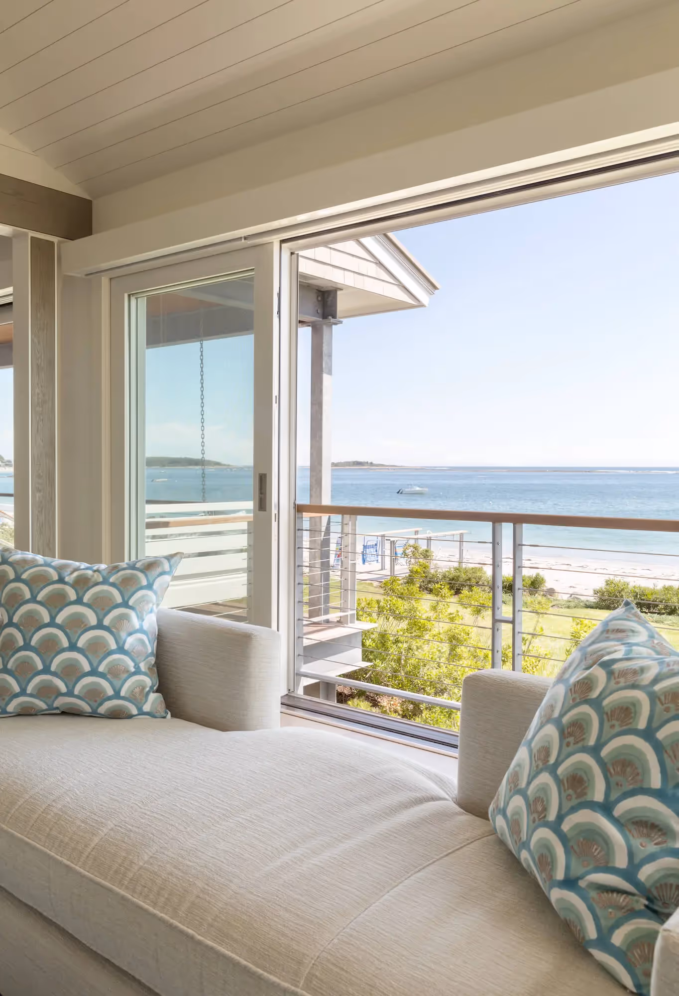 Cozy window seat overlooking beach with blue-patterned cushions