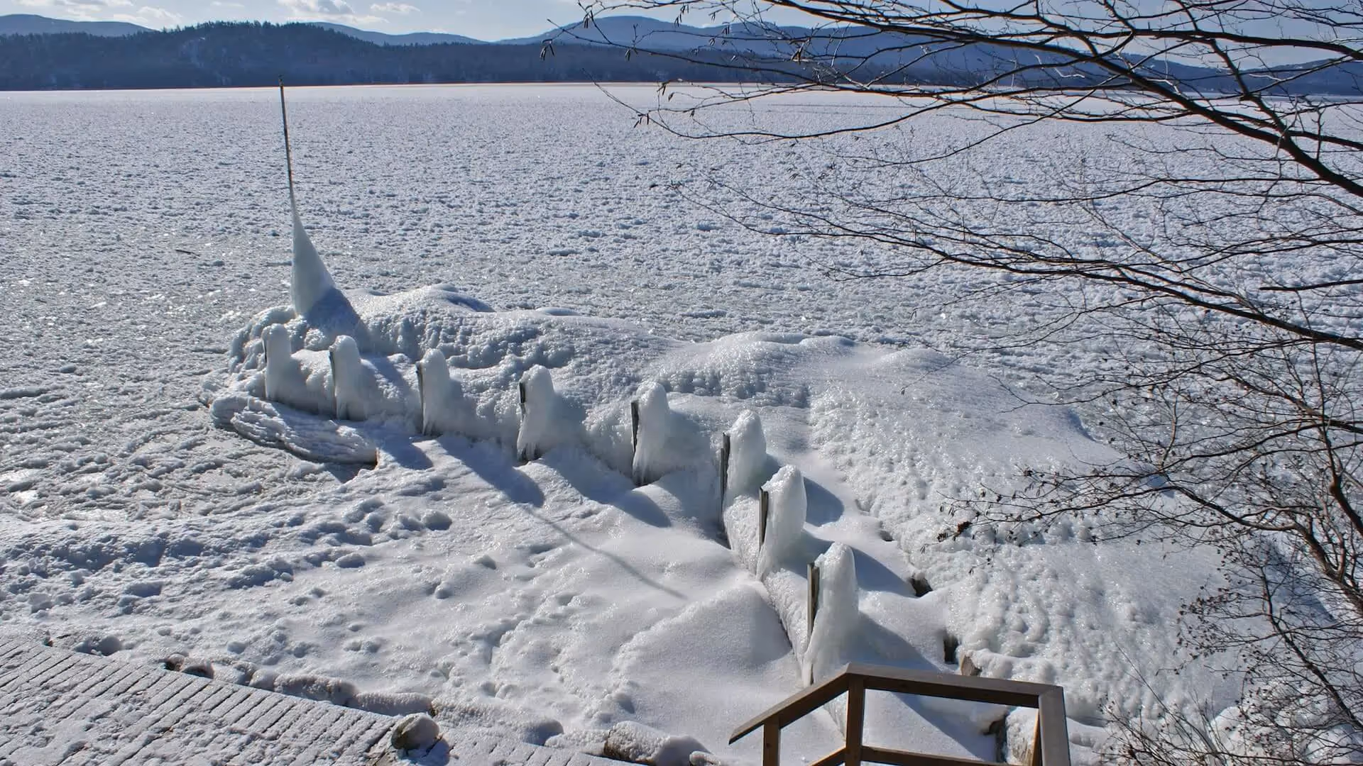 Frozen lake with jagged ice formations and snow-covered mountains