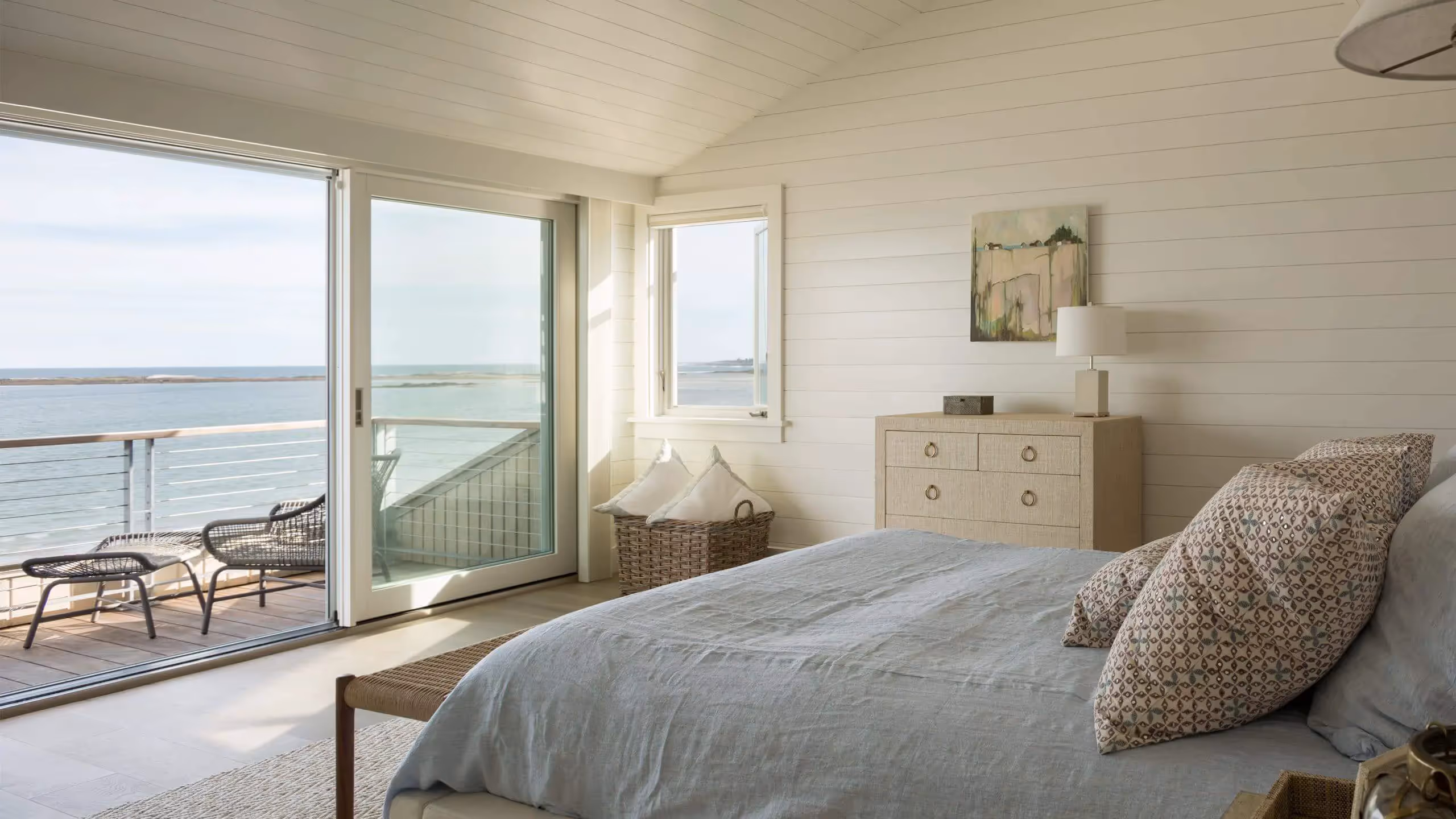 Coastal bedroom with ocean view, white shiplap walls, and peaceful decor