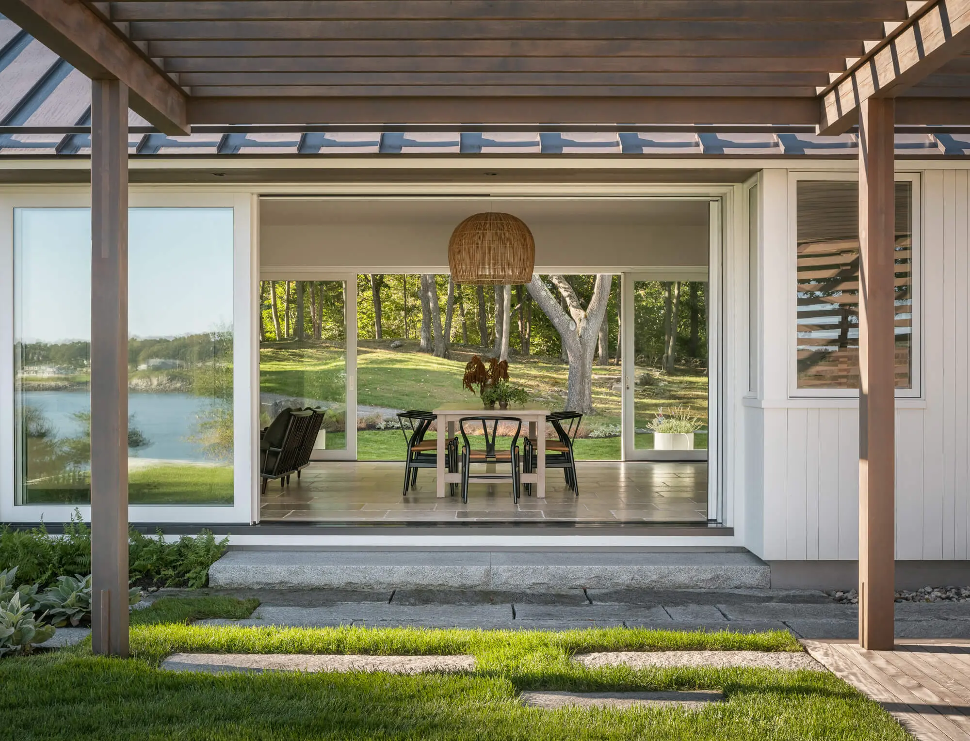 Modern dining area with lake view through large windows and wooden pendant