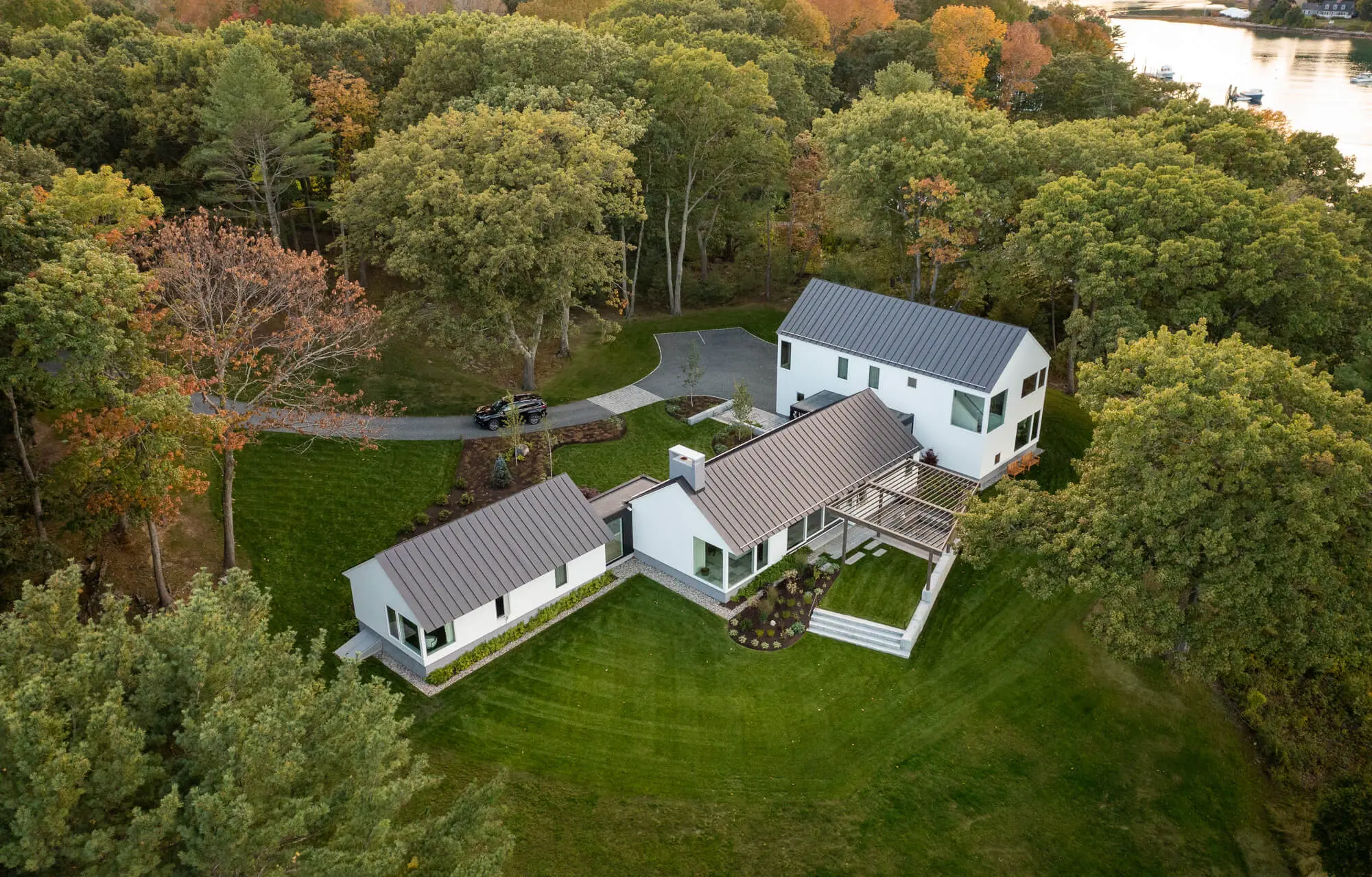 Modern white houses nestled in autumn forest with winding driveway