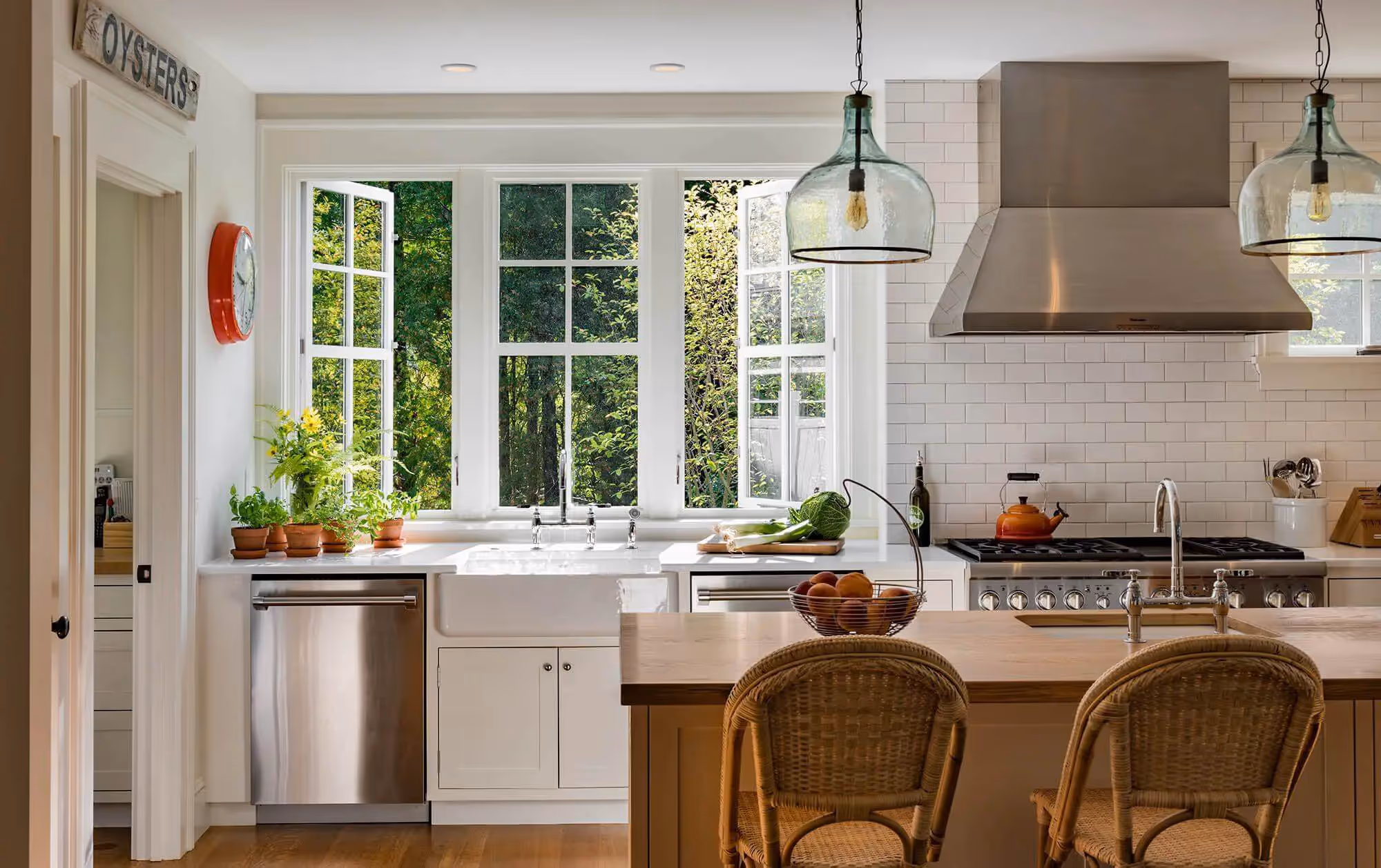 Bright kitchen with large windows, white cabinets, and wicker chairs