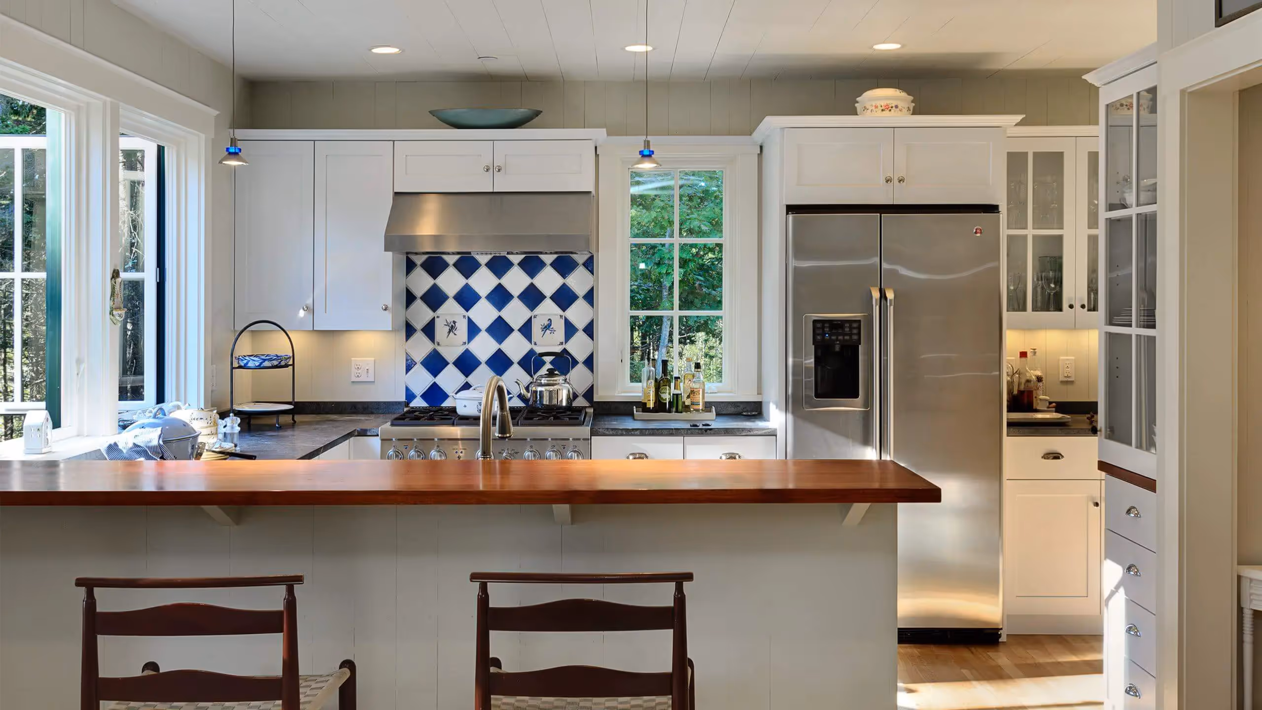 Modern kitchen with white cabinets, blue and white tile backsplash, wood counter