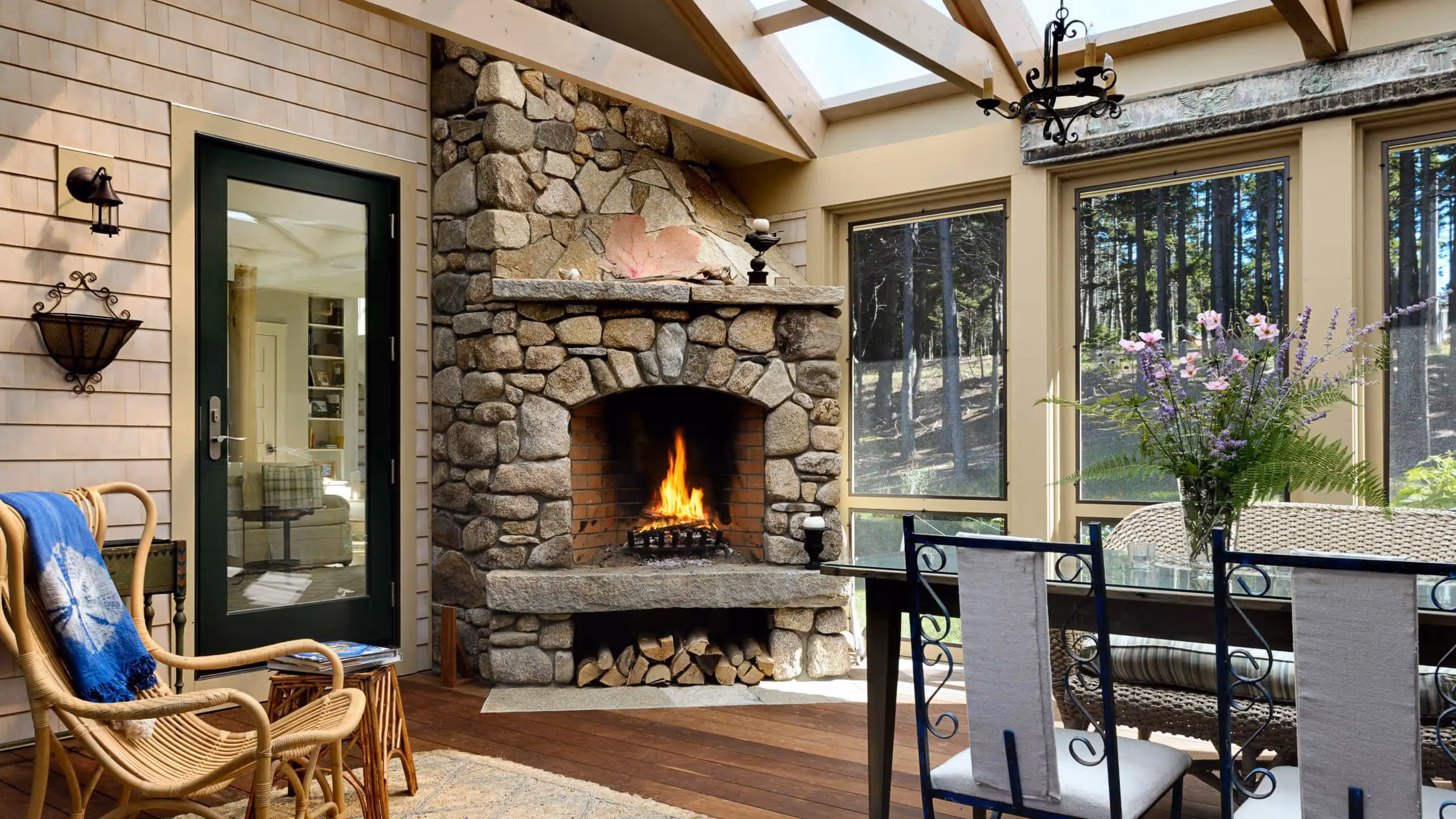 Cozy stone fireplace in sunlit room with forest view and wicker furniture