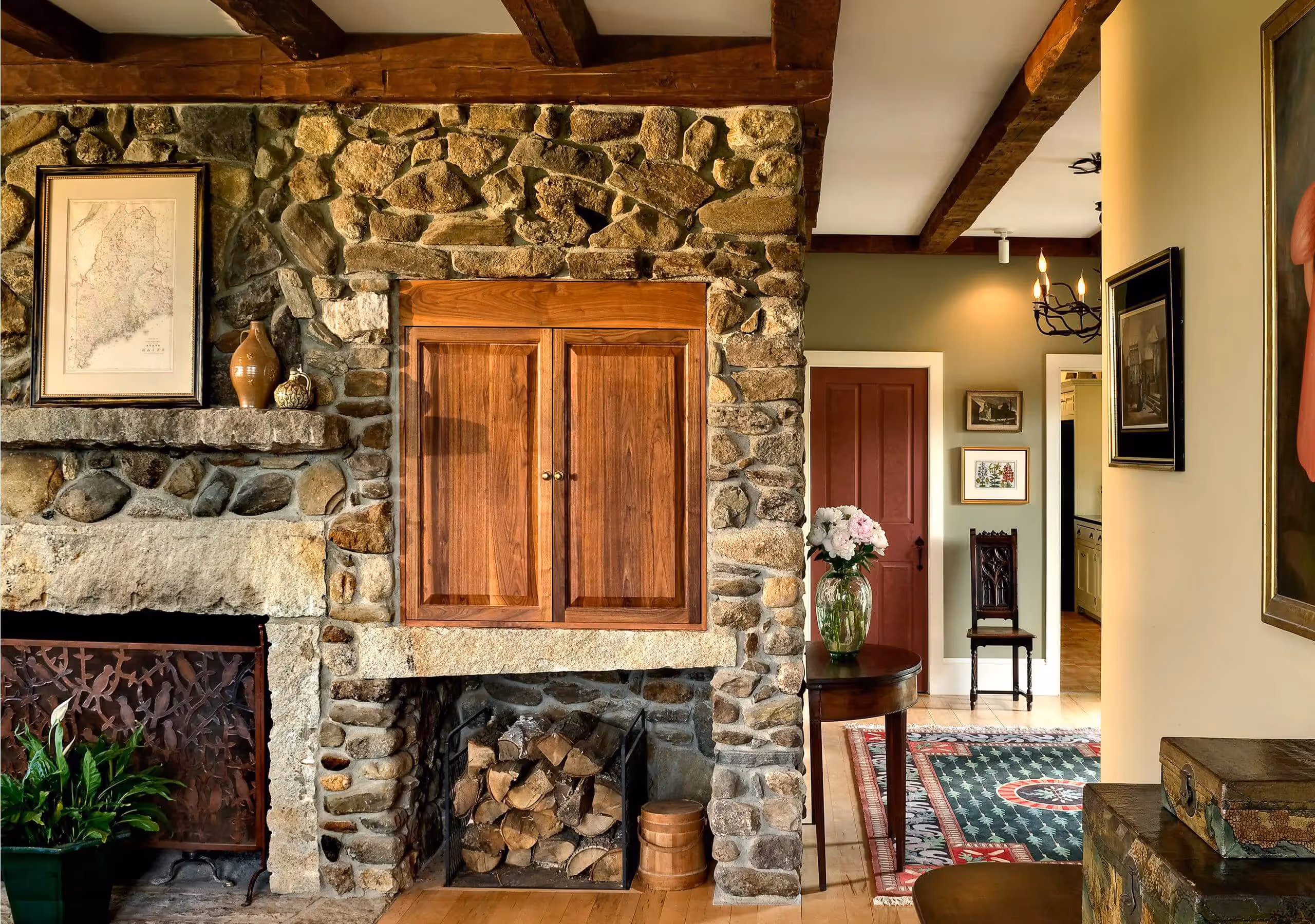 Rustic stone fireplace with wooden cabinet and stacked firewood