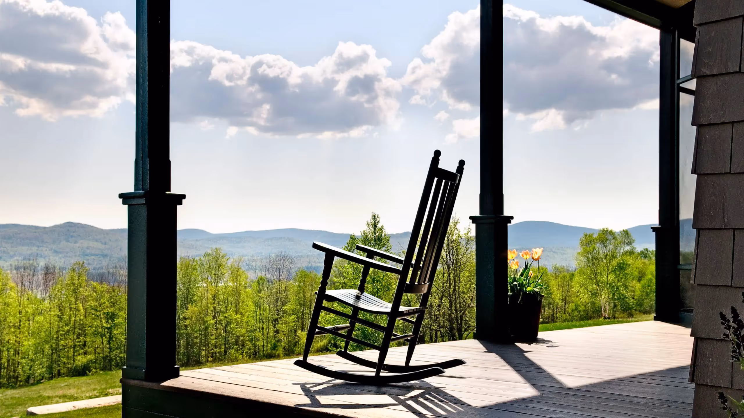 Black rocking chair on porch overlooking scenic mountain and forest landscape