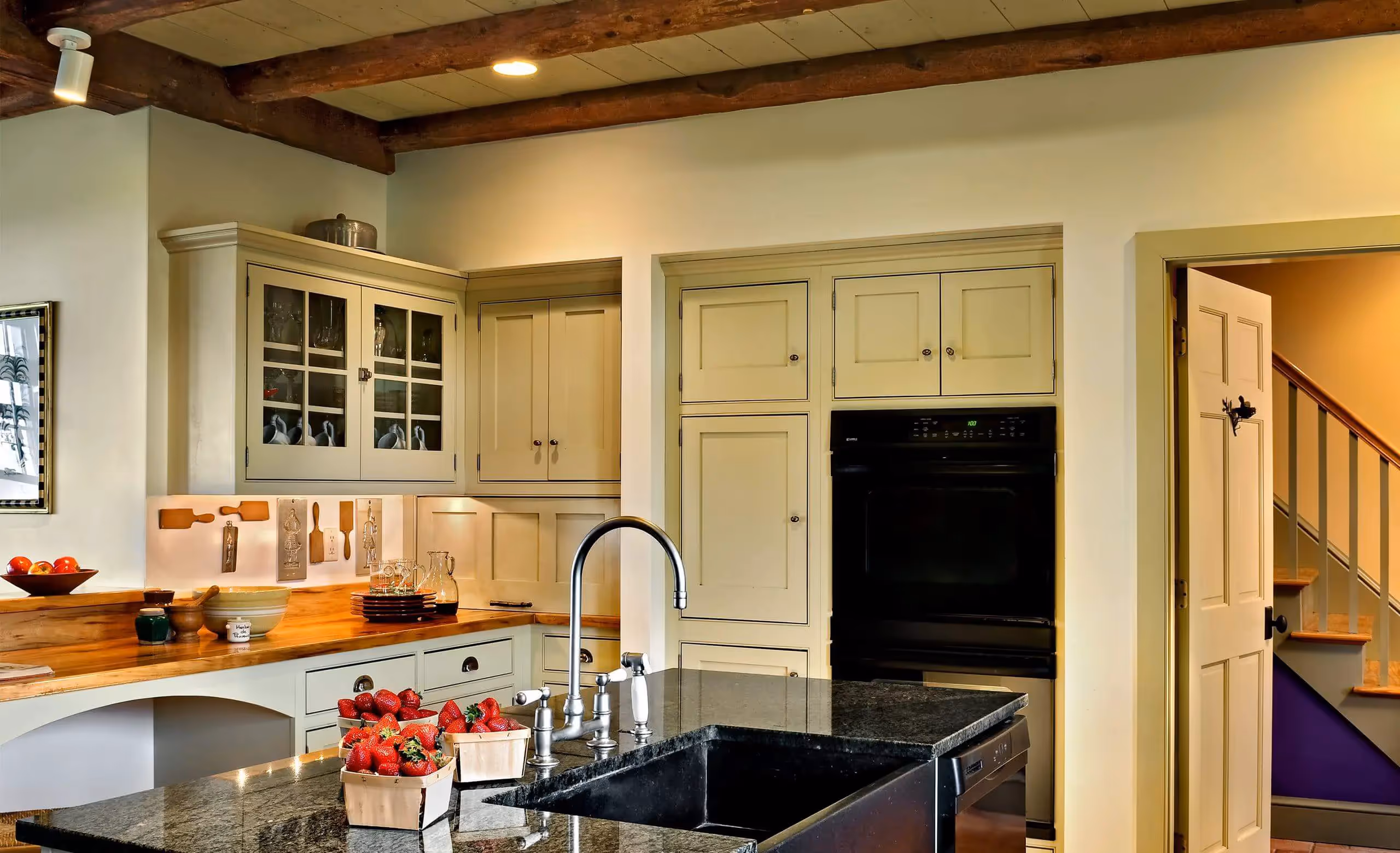 Rustic kitchen with wooden beams, cream cabinets, and fresh strawberries