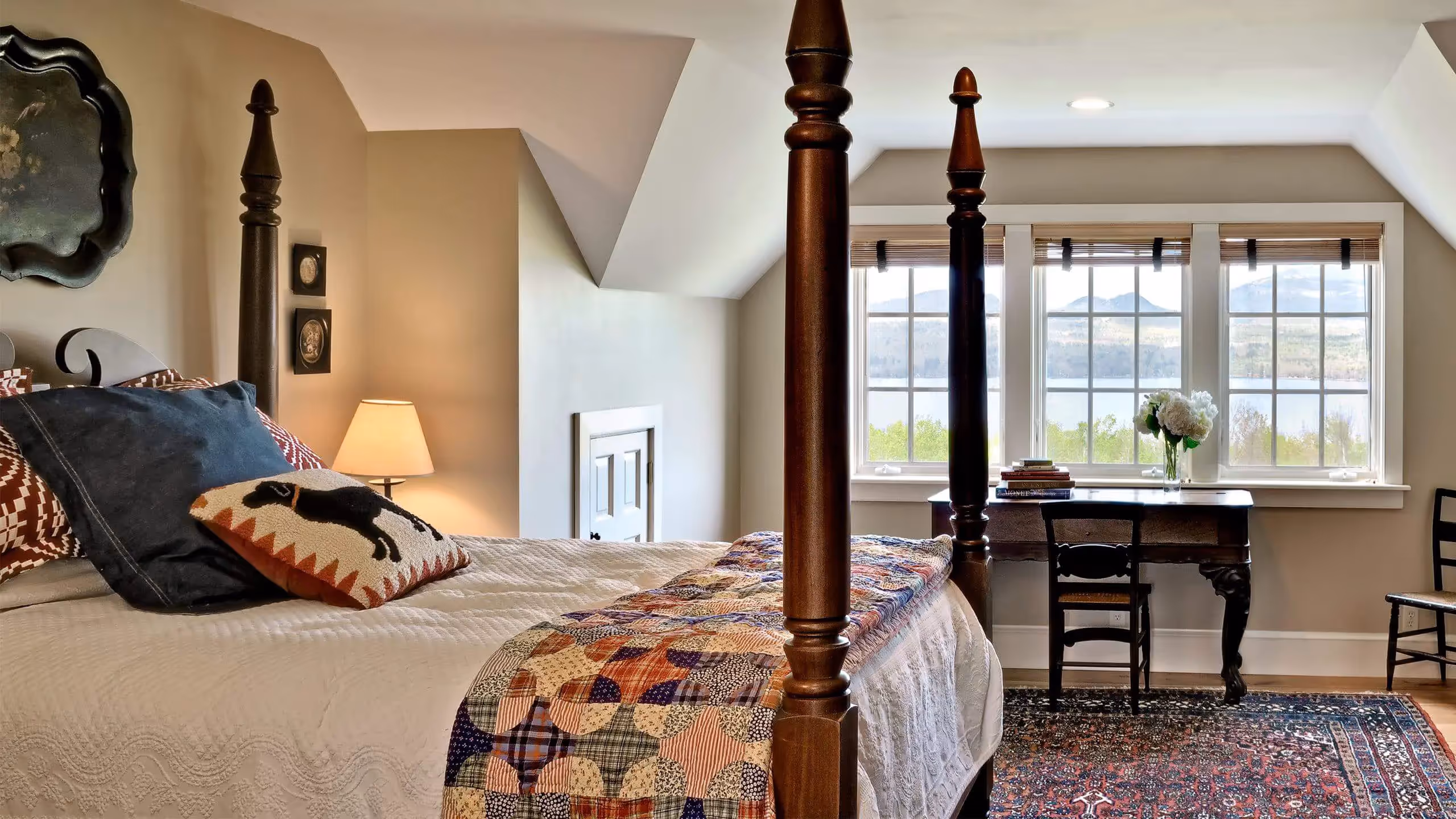Cozy bedroom with four-poster bed, patchwork quilt, and lake view window