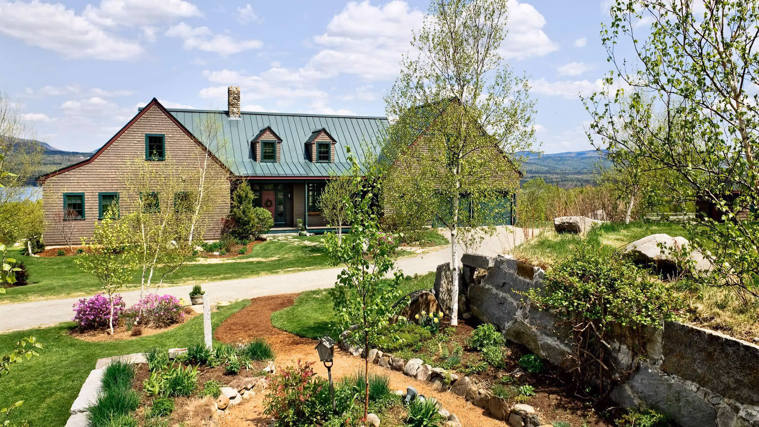 Rustic green-roofed house with landscaped garden and mountain view