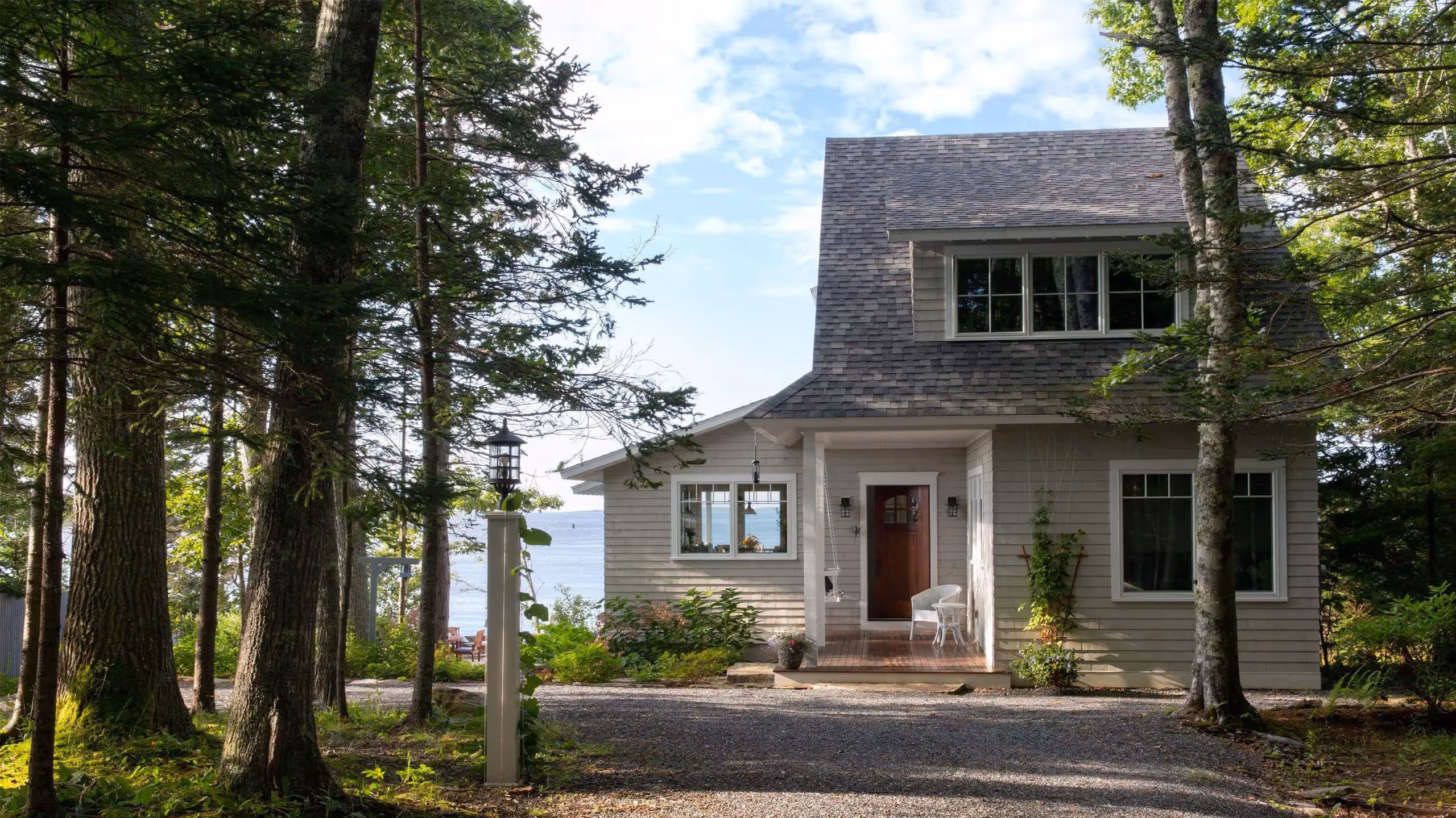 Coastal cottage nestled among trees with ocean glimpse through windows