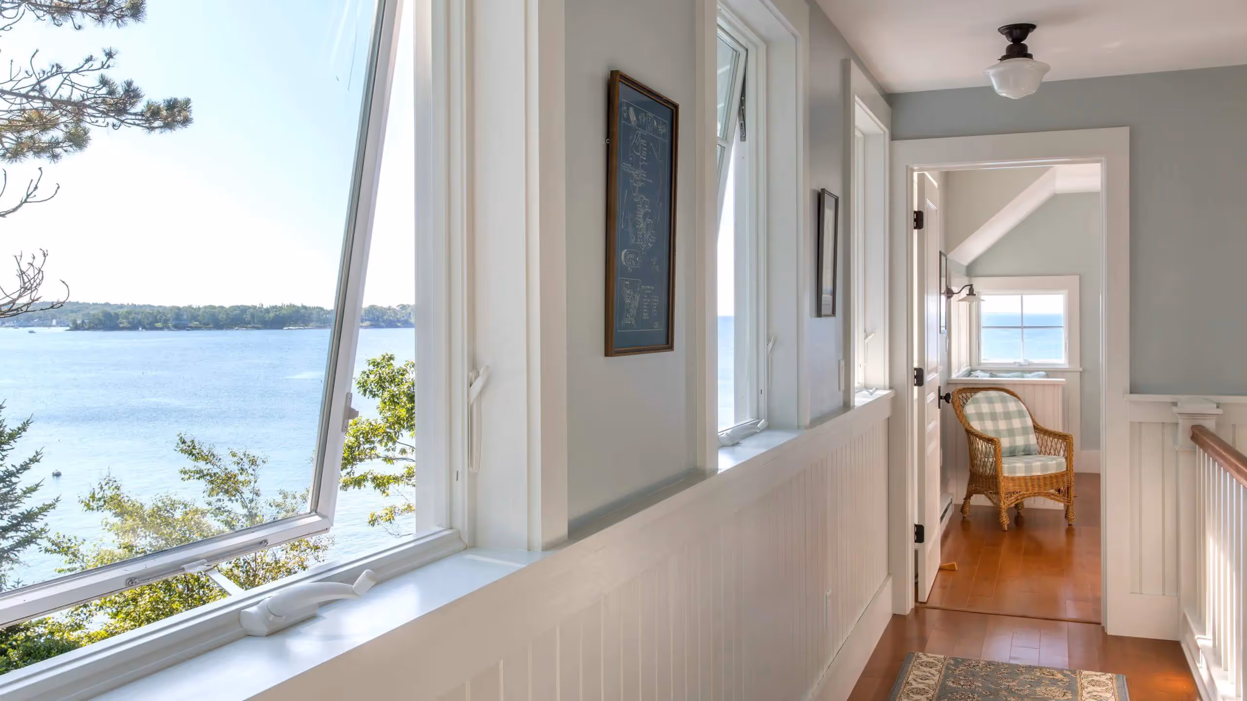 Bright hallway with large windows overlooking scenic lake and trees