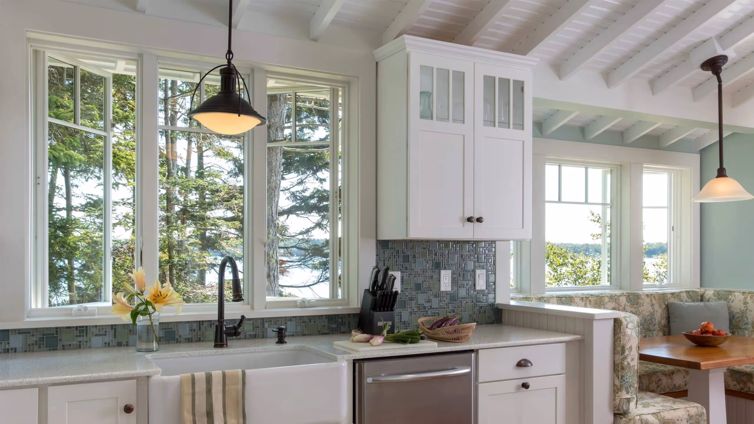 Bright kitchen with large windows overlooking forest and water view