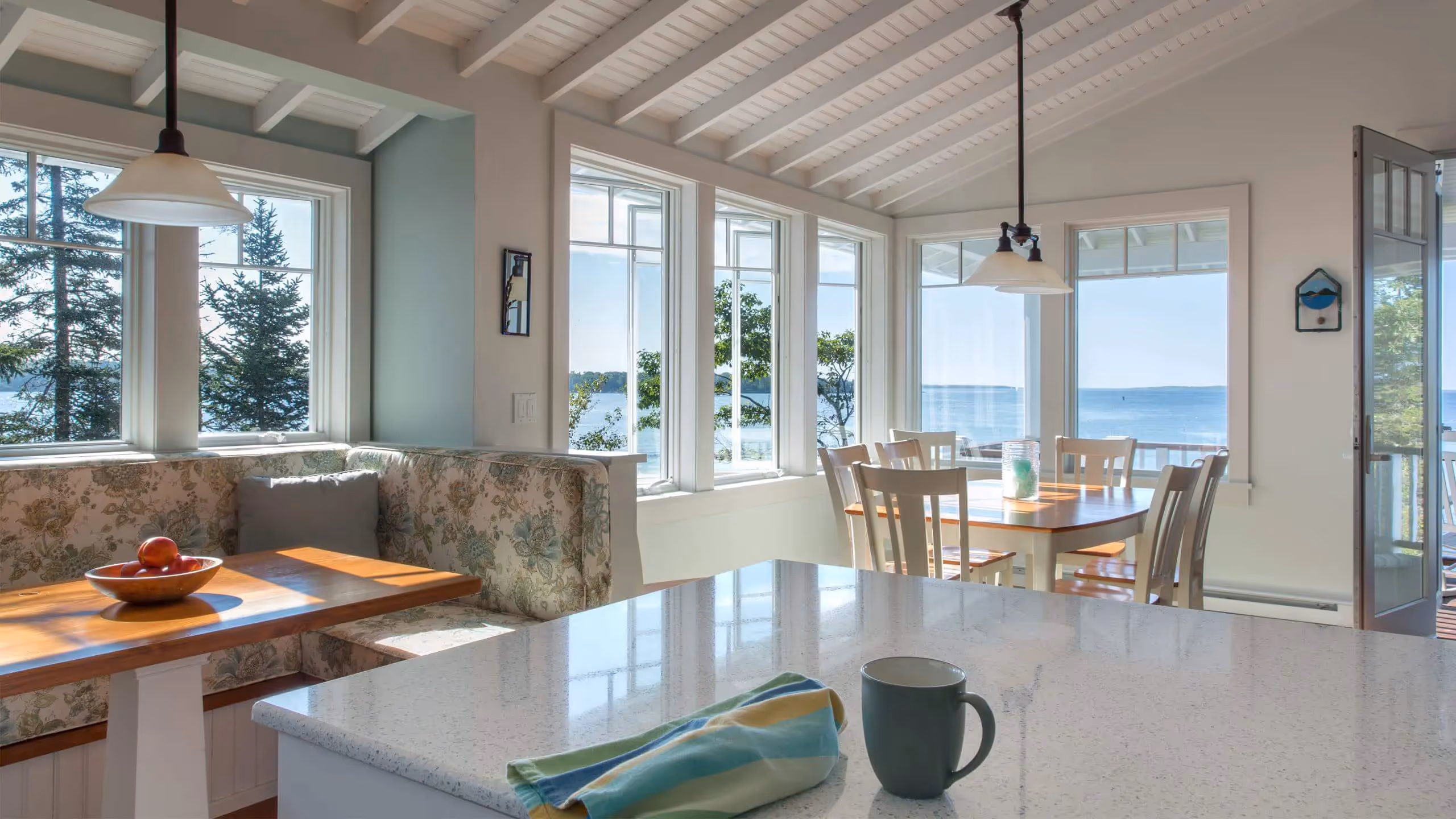 Bright coastal kitchen with ocean view, white decor, and large windows