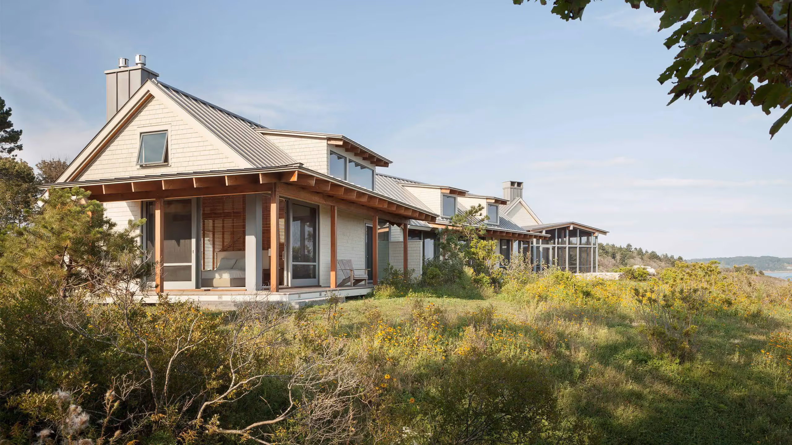 Modern beach houses nestled in coastal vegetation with metal roofs