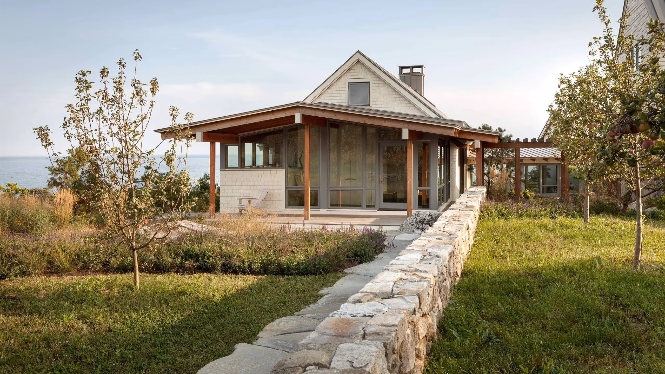 Modern beach house with stone wall, trees, and ocean view