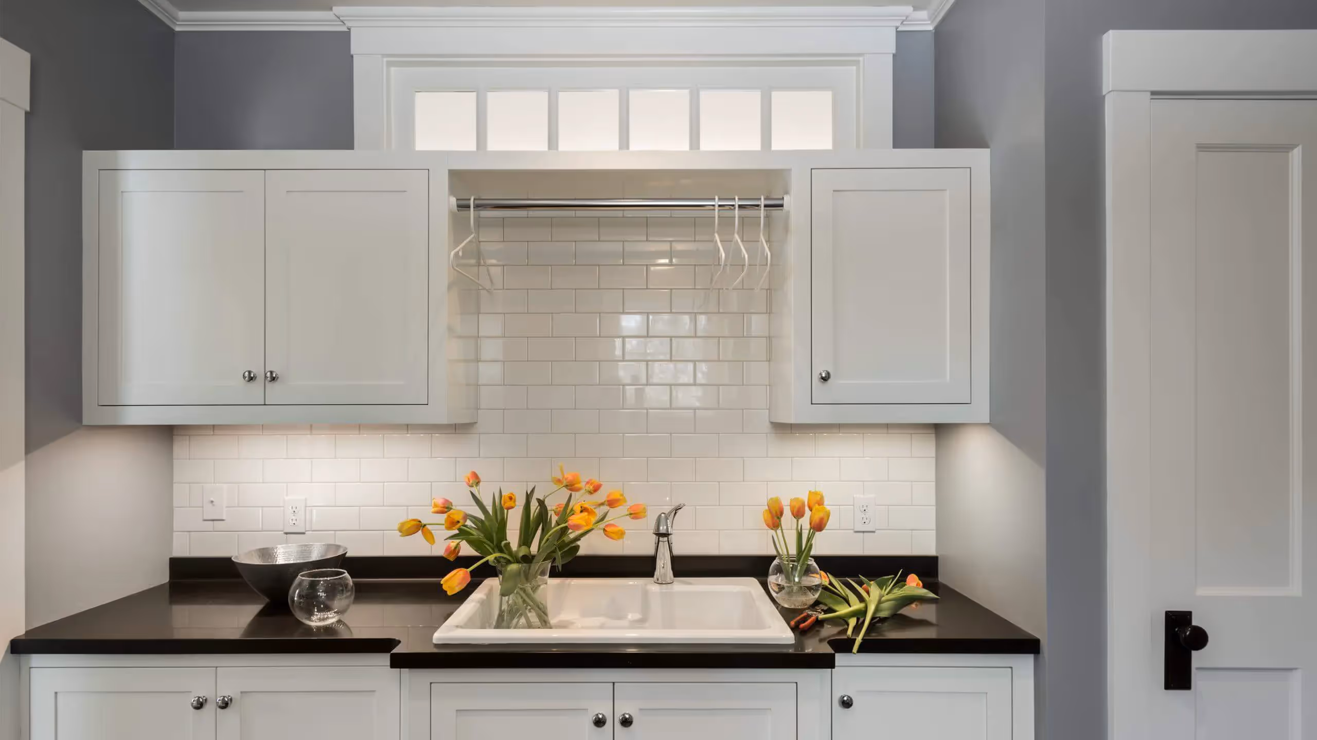 White kitchen with black countertop and yellow tulips in glass vases