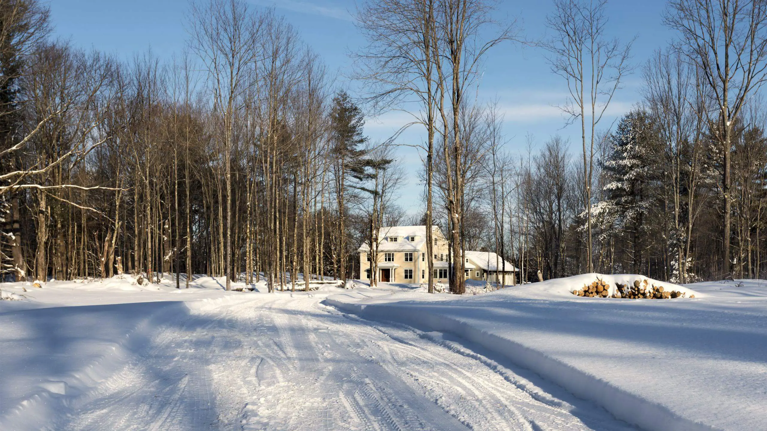 Snowy winter landscape with white house nestled among bare trees